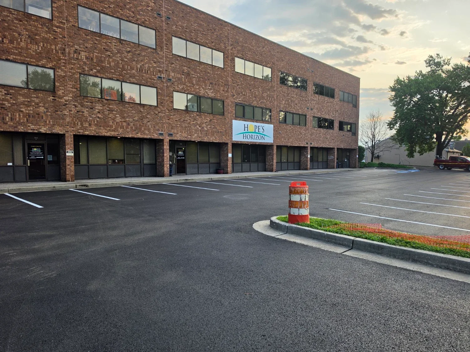 Newly paved asphalt parking lot with white stall striping and accessible space marking beside a brick office building